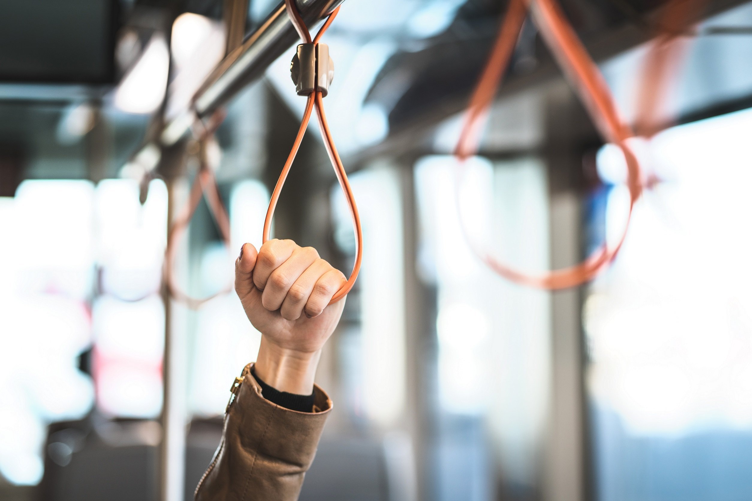 Hand greift eine Schlinge im Bus zum Festhalten.