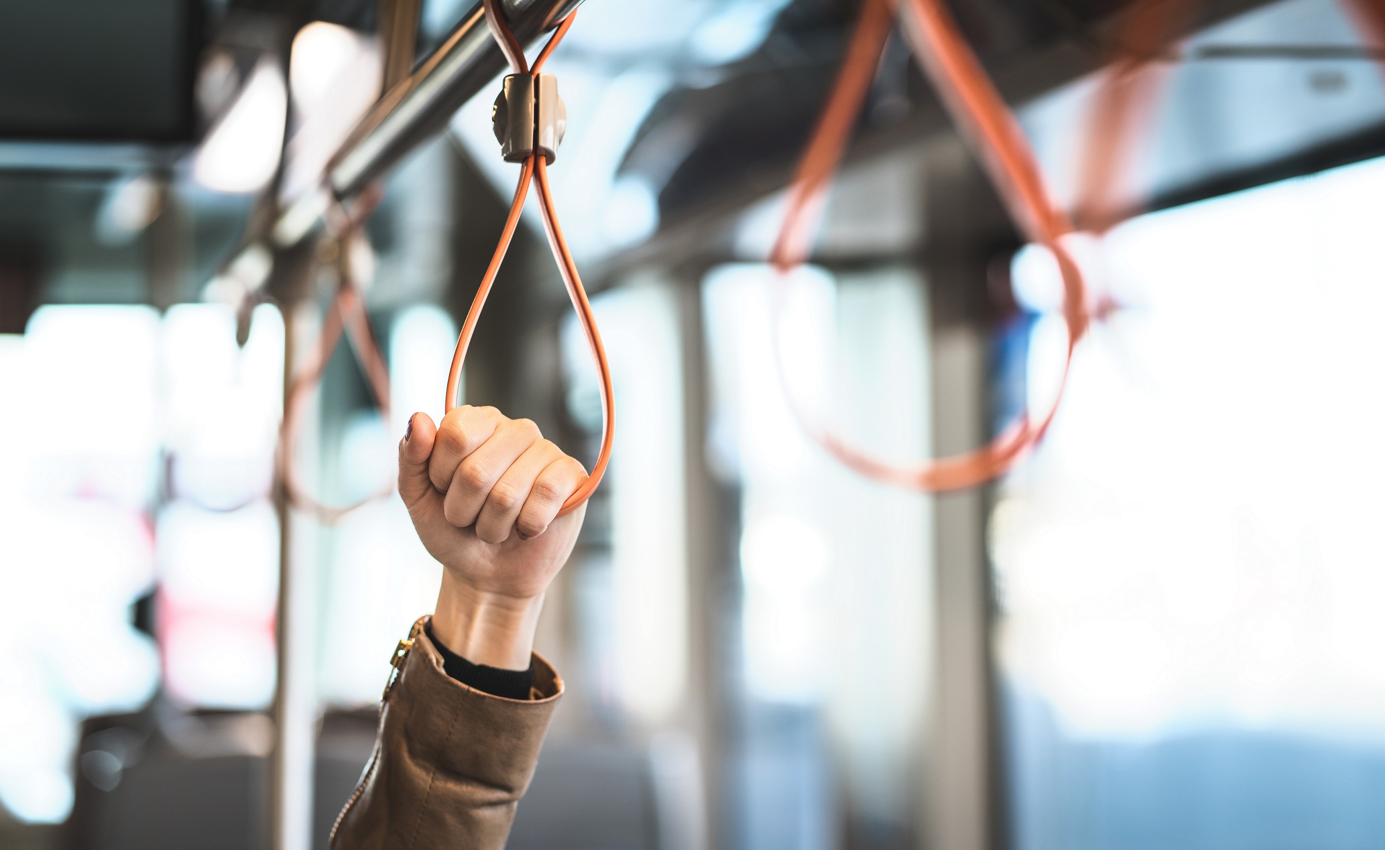 Hand greift eine Schlinge im Bus zum Festhalten.