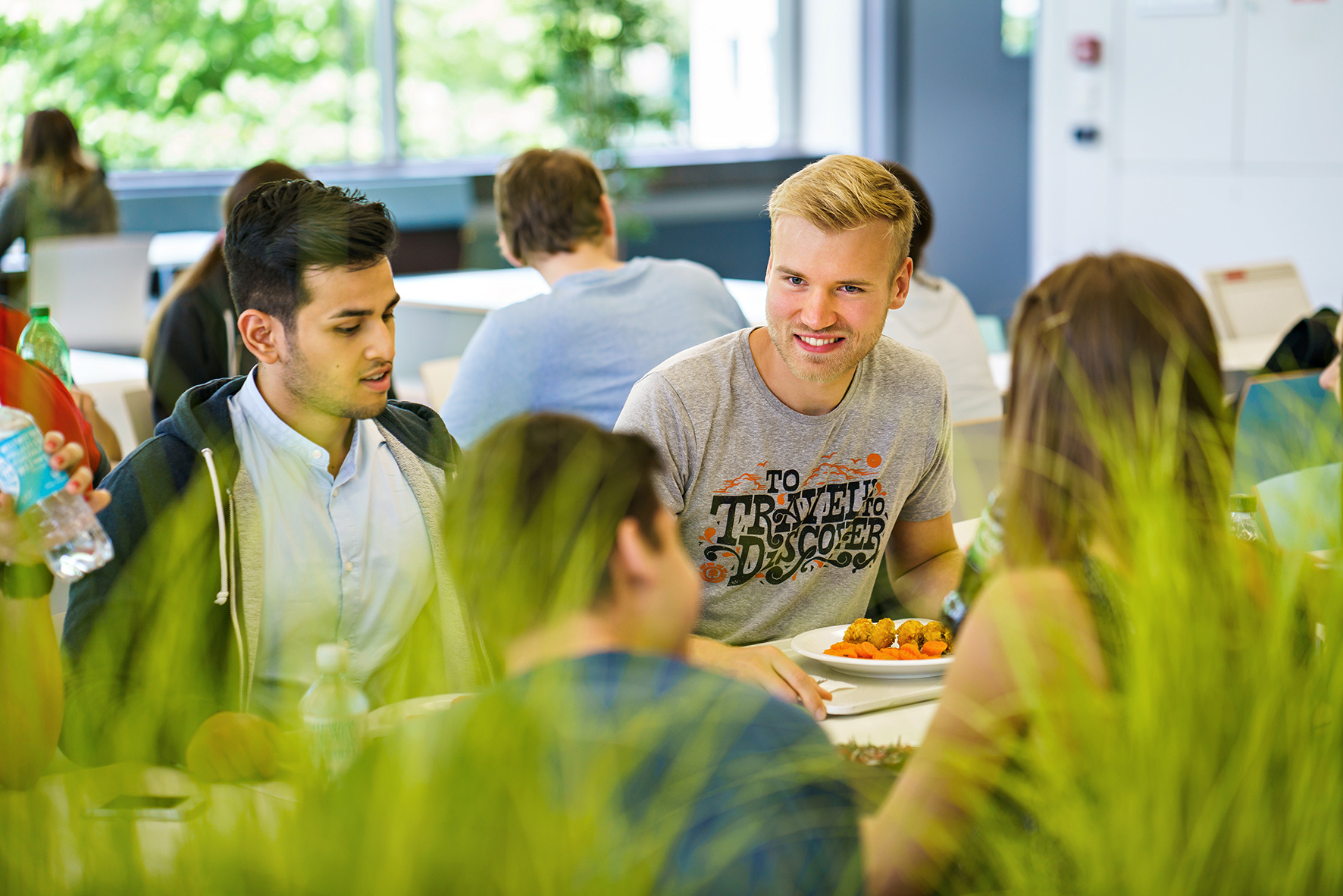 Studierende sitzen am Tisch in der Mensa Süd und unterhalten sich.